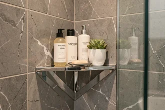 Étagère d'angle chromée dans une douche en marbre gris avec rangement de produits cosmétiques