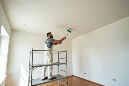 Peintre professionnel sur échafaudage aluminium en train de peindre un plafond de 50m2 dans un salon résidentiel