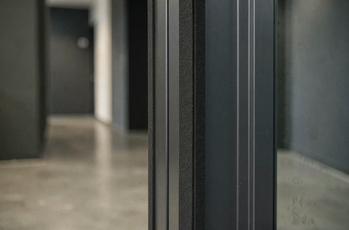 Protège-doigts anti-pincement anthracite discret sur le bord d'une porte moderne dans un couloir de logement locatif