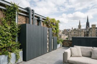 Terrasse urbaine contemporaine avec éléments techniques dissimulés derrière des claustra en bois anthracite et plantes grimpantes